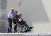 Zwei Personen schieben eine Frau im Rollstuhl